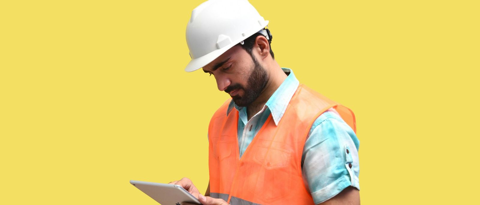 A worker in a hard hat reviewing findings on a tablet