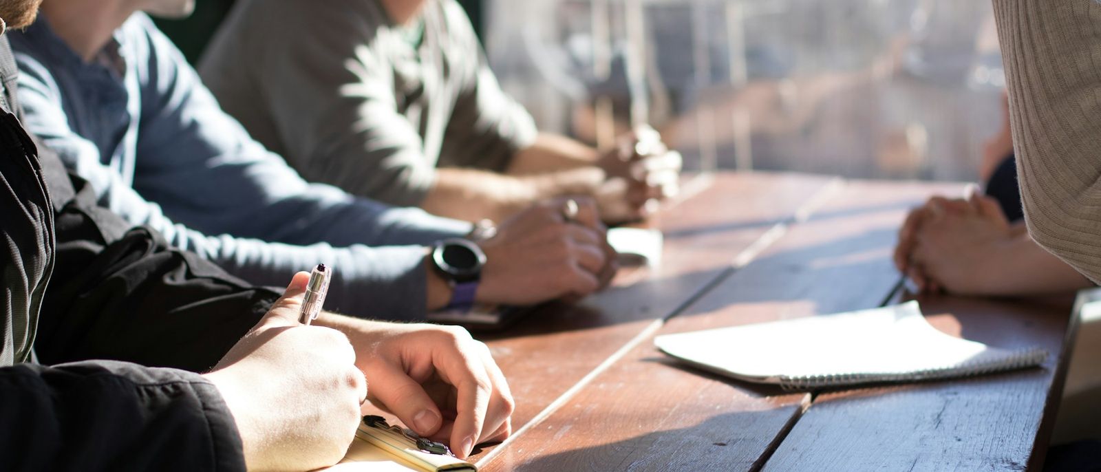 A small team around a table taking notes in a meeting