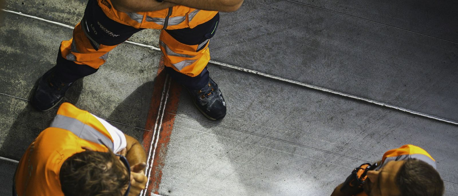 Workers in orange hi-vis vests gathered on a site