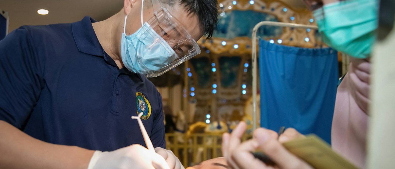 A dentist and assistant working on a patient in a treatment room